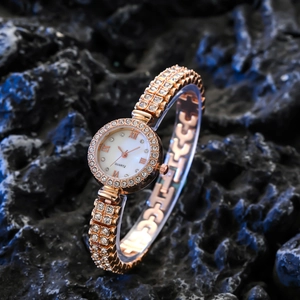 Luxury rose gold women's watch with crystal-encrusted bezel and strap on a black rock background