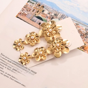 Detailed close-up of golden metal flower earrings with pearls on fashion jewelry card