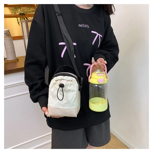 Detailed view of cream nylon drawstring crossbody bag with adjustable black shoulder strap