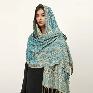 Detail of teal cashmere-feel shawl with gold paisley patterns and fringed edges