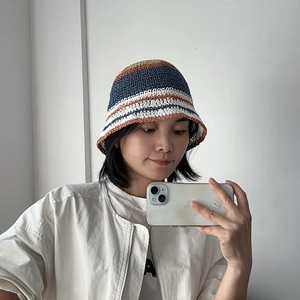 Detail of a woman wearing a handmade striped straw bucket hat for summer sun protection.
