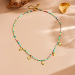 Colorful acrylic bead necklace with five golden sunflower pendants on beige background