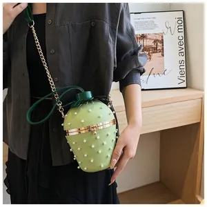 Détail du sac bandoulière en forme de fraise vert avec des perles blanches décoratives