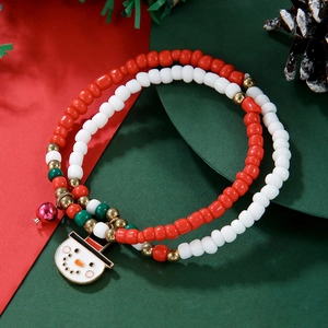 Detail of Christmas beaded bracelet with snowman and bell charms on festive background