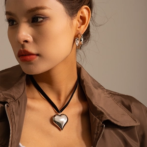Close-up of polished silver heart pendant with black choker and matching earrings
