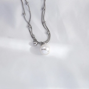 Close-up of multi-layer silver snake chain with pearl pendant on white satin fabric
