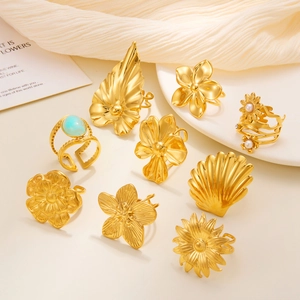Golden titanium steel rings with floral designs and turquoise on a ceramic plate