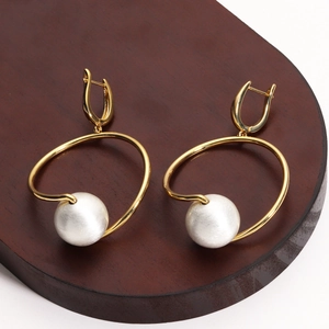 Detailed close-up of 18K gold plated spiral earrings with elegant large white pearls