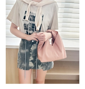 Detail of soft pastel pink cloud bag paired with a graphic tee and denim skirt