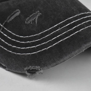 Detailed close-up view of distressed washed cotton baseball cap featuring contrast white stitching.