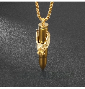 Detailed view of a gold bullet pendant with embossed eagle design on a black background