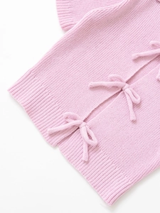 Detailed view of pink knitted top featuring cute bow-tie accents and ribbed texture