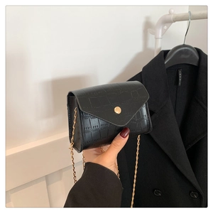 Macro detail of the glossy black crocodile-embossed texture and golden buckle on the bag