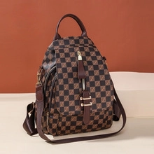 Detailed view of checkered brown PU leather texture and gold-tone zippers on backpack