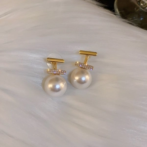 Detailed view of a gold T-shaped earring with a white pearl and sparkling crystals