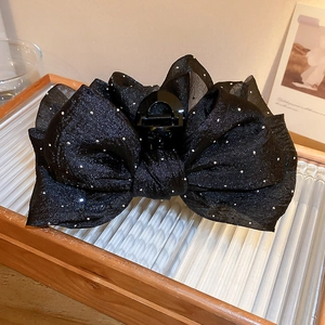 Gros plan d'une pince à cheveux avec nœud en tulle noir et paillettes argentées