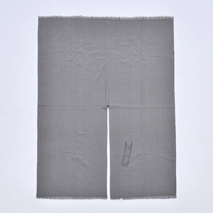Detail of grey tasseled poncho showing textured jacquard fabric and side buckle strap