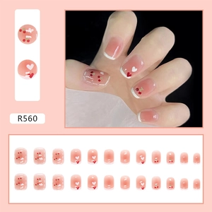 Detail of short pink press-on nails with cherry accents and white heart French tips