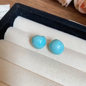 Macro shot of blue resin tulip bead earrings with marble texture in a jewelry box
