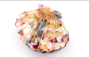 Macro detail of shell-shaped acetate hair claw with artistic colorful swirl patterns