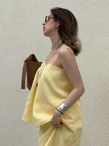 Detail of yellow cotton-linen camisole and fishtail skirt set with brown leather bag