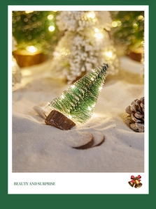 Close-up of a mini Christmas tree with warm LED lights and artificial snow on a wood base