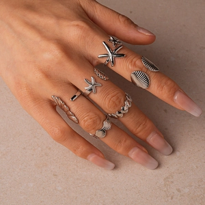 Detailed view of seven silver rings featuring starfish and shell ocean-themed designs