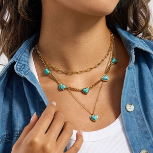 Collier doré multi-rangs avec pendentifs cœurs en turquoise sur chemise en denim