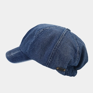 Detail of vintage blue denim newsboy cap with leather label and metallic rivet