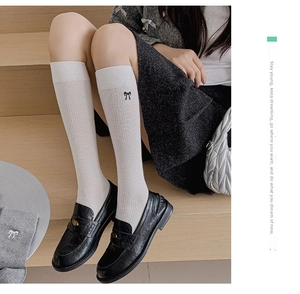 Close-up of white over-the-knee socks with black bow embroidery in Japanese style