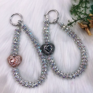 Detail of luxury rhinestone heart phone charms with shimmering beads on white fur background
