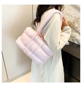 Gros plan d'un sac cabas matelassé à rayures roses et blanches porté à l'épaule