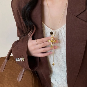Detail of a vintage golden cross pendant necklace with rhinestones on a brown blazer