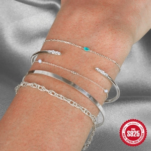 Macro shot of 925 sterling silver bracelets and bangles set with green zircon on silk