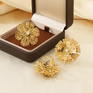 Vue détaillée de trois bagues fleurs dorées avec perles sur un tissu en soie élégant