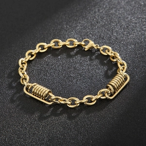 Detail of golden O-chain bracelet featuring spring cylindrical charms and lobster clasp