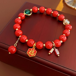 Gros plan détaillé d'un bracelet en perles rouges avec un pendentif doré Fu sur bois