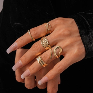 Detailed close-up of 5-piece gold geometric ring set on black velvet showing metal textures
