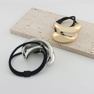Close-up of gold and silver metallic streamlined hair ties on a textured stone surface