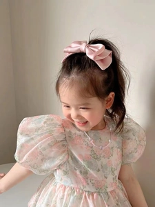 Detail of a pink satin bow hair clip worn by a girl, showing smooth fabric texture