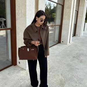 Women's brown wool zip jacket paired with black wide-leg pants and a suede handbag