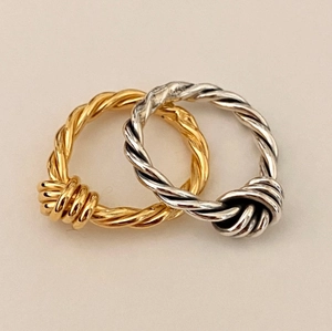 Detail view of intertwined 925 silver knot rings in gold and silver metallic finishes