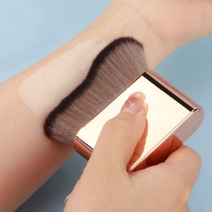 Macro view of wave foundation brush applying liquid makeup smoothly on the skin