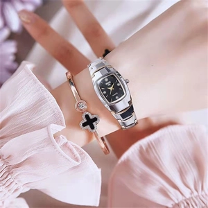 Elegant silver quartz watch with black barrel dial layered with a clover bracelet