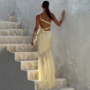 Detail of light yellow satin dress featuring an open back with lace-up bow and tulle hem