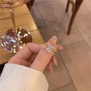 Gros plan d'une bague nœud dorée avec zircons pavés et double anneau portée à la main
