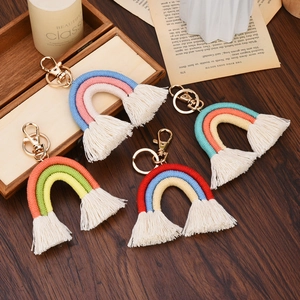 Detail view of four handmade rainbow macrame keychains with tassels on a rustic table