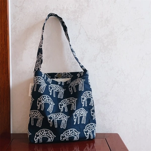 Detailed embroidery of white sheep patterns on navy blue canvas bag with snap button