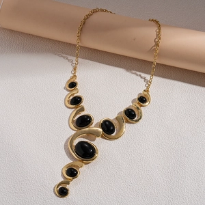 Detail of vintage gold necklace featuring curved S-shape links and black oval gemstones