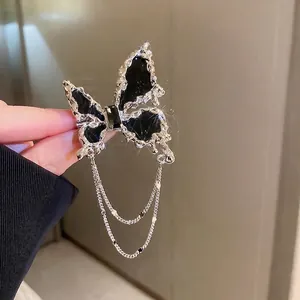 Broche papillon en métal liquide argenté avec résine noire et pompon chaîne